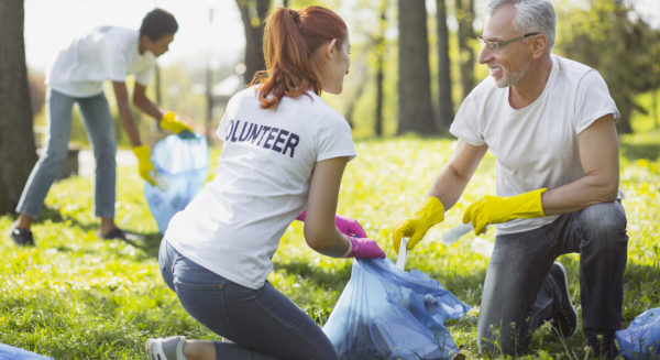 Non profit volunteer. Vigorous two volunteers holding garbage bag and chatting