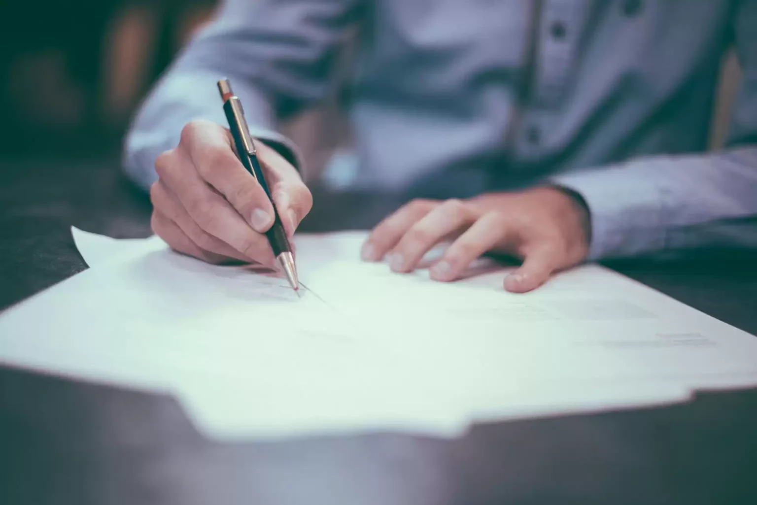 A man in business attire writing on a piece of paper